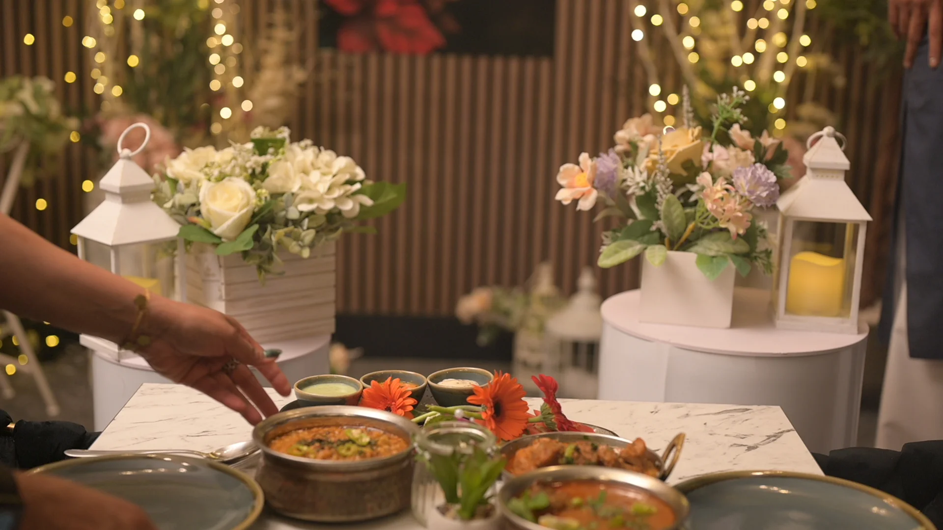 Karahi dishes served at a candlelit table set with flowers and lanterns